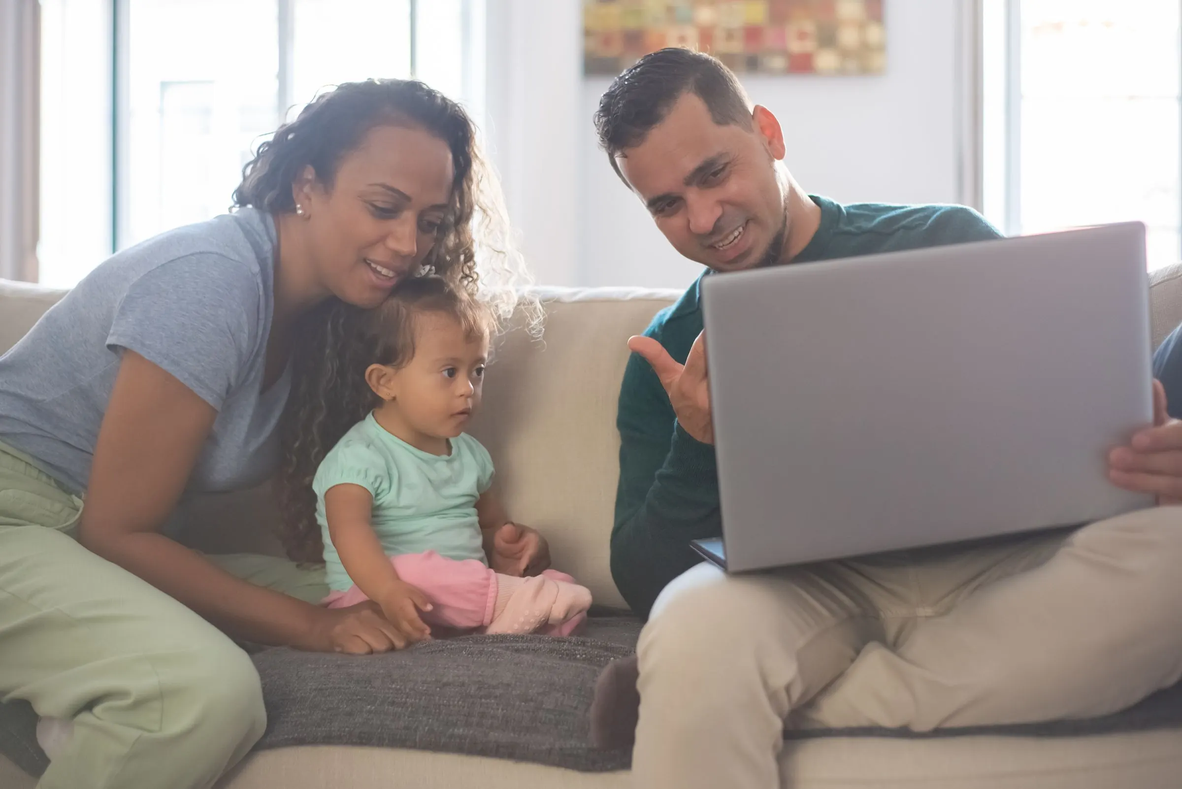 Familia en el sofá de su sala mirando una computadora portátil.